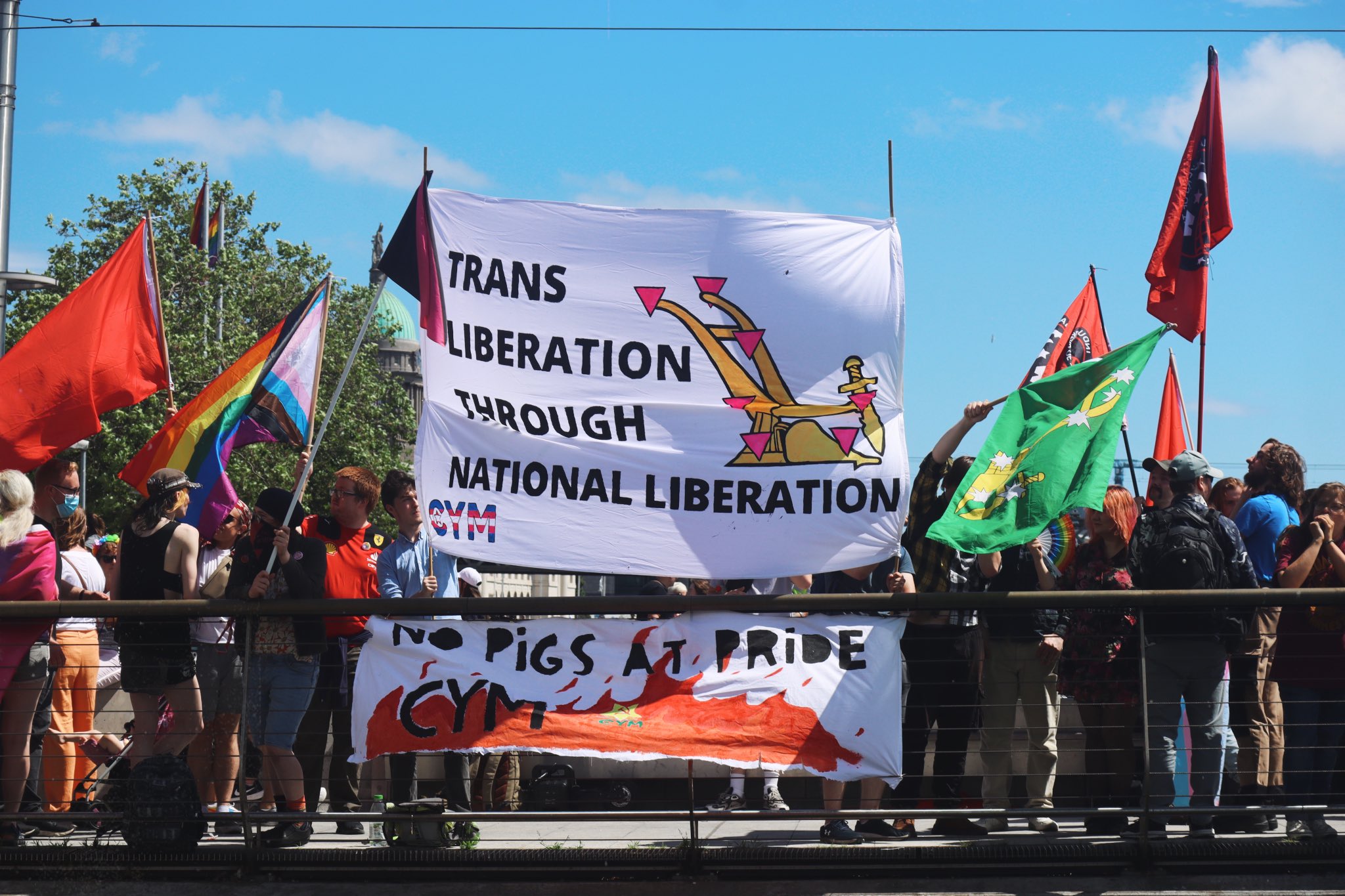 Two banners, one reading "Trans Liberation through National Liberation", another reading "No pigs at Pride" at alternative pride